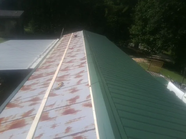 Old rusted panels beside newly installed green metal roofing — Wind Damage Roof Repair by Roofing Brothers in Norwood