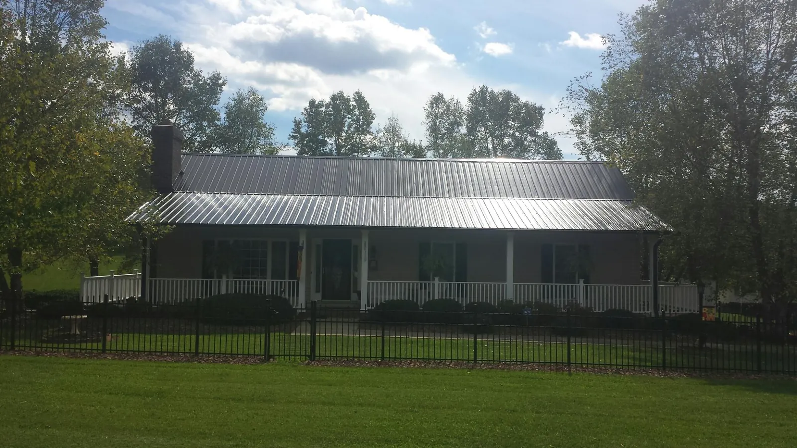 Gray metal roof on a brick ranch with a full width front porch — Gutter Guard Installation work by our crew in Norwood