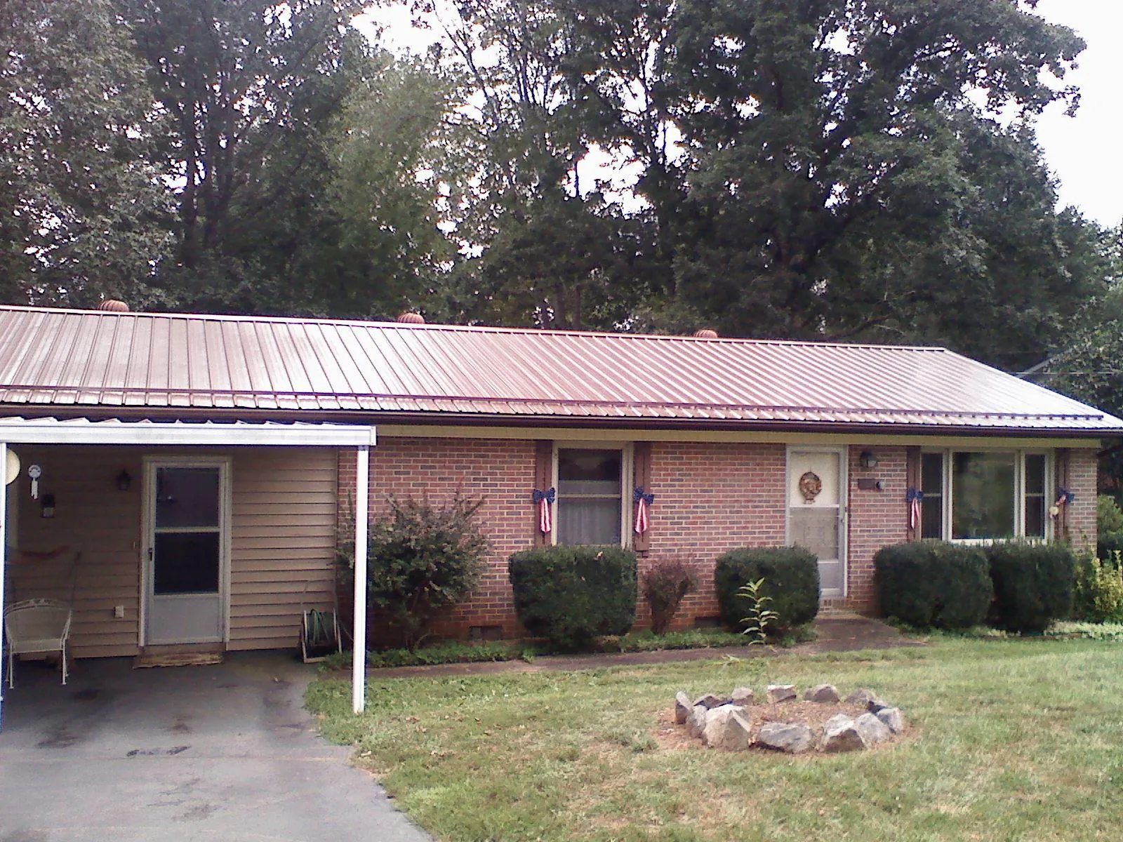 Bronze metal roof and carport on a brick ranch home — Roof Repair work by our crew in Norwood
